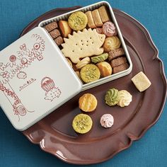 a brown plate topped with cookies and crackers next to a container filled with treats