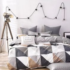 a bed with grey and white checkered comforter set on top of it next to a tripod light