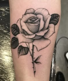 a black and white rose tattoo on the leg