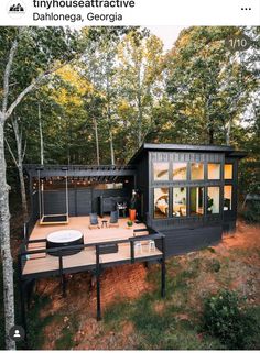 a small house with a deck in the middle of it and lots of trees around