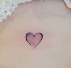 a small heart tattoo on the back of a woman's stomach, with pink ink