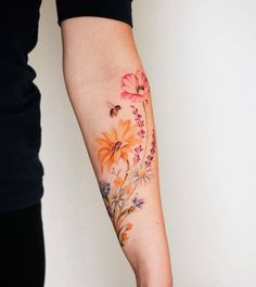 a woman's arm with flowers on it and a bee flying over the flower