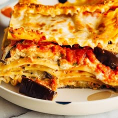 a white plate topped with lasagna covered in cheese