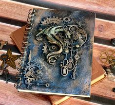 an open notebook sitting on top of a wooden bench covered in assorted metal items