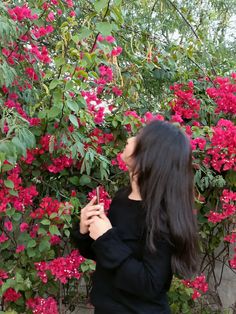 a woman standing in front of pink flowers