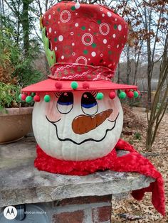 a large pumpkin with a hat on it's head sitting on top of a stone wall