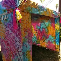 a colorful tent is set up on the grass with tassels hanging from it's sides