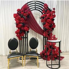 red flowers are arranged on black chairs in front of a white backdrop and drapes