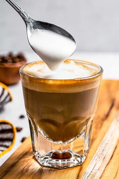 a spoon is pouring milk into a cup of coffee