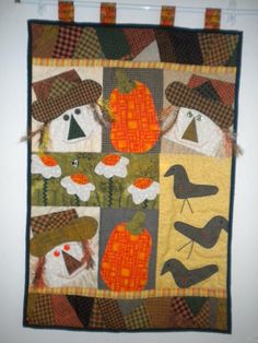 a quilted wall hanging with birds, pumpkins and scarecrows on it