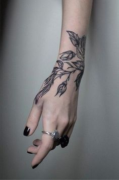 a woman's hand with a tattoo on her left arm and leaves on the wrist