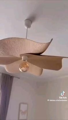 a ceiling fan that is hanging from the ceiling in a room with white walls and curtains