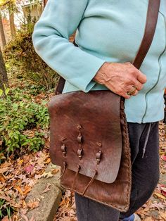 Win Baker Large and spacious shoulder bag with handmade ornamentation on front outer flap. Made in USA of 100 percent cowhide. Has lovely overhand stitching in bold 1/2"  leather thongs, all the way around, all 3 sides. Top edge is finished with machine stitch. Huge!  Deep color of dark chocolate with chestnut undertones looks and feels brand new. Comes with a large and extremely well ade 2" wide strap with deem stitches on both sides and a dynamite gold heavy buckle  which you can adjust accord Traditional Leather Saddle Bag For Everyday Use, Traditional Leather Saddle Bag With Adjustable Strap, Artisan Hand Tooled Leather Saddle Bag, Artisan Hand-tooled Leather Saddle Bag, Traditional Leather Saddle Bag, Leatherworking Tools, Deep Colors, Wide Straps, 100 Percent