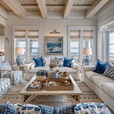 a living room filled with white furniture and blue pillows on top of it's couches