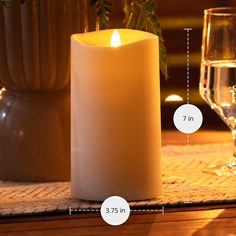 a white candle sitting on top of a wooden table next to a glass of wine