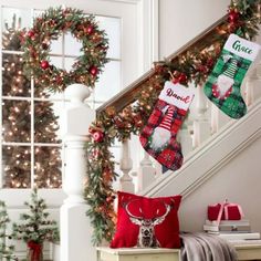 christmas stockings hanging from the banisters in front of a staircase decorated with holiday decorations