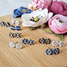 six pairs of earrings sitting on top of a wooden table next to flowers and a blue ribbon