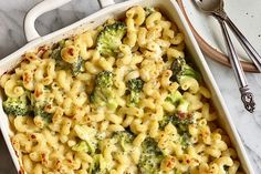 a casserole dish filled with macaroni and broccoli on a marble table