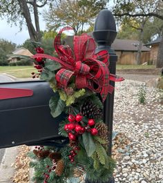 a mailbox decorated for christmas with holly and pine cones, red berries and bows