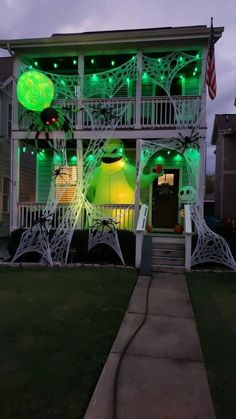 a white house with green lights on it's front porch and stairs to the second floor