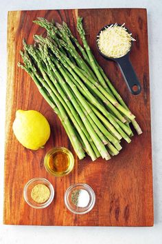 asparagus, lemons, garlic and seasoning on a cutting board with spices