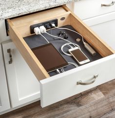 an open drawer in a kitchen with electronics and charging devices inside the drawers on each side