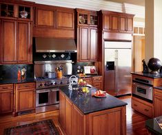 a large kitchen with wooden cabinets and black counter tops, along with stainless steel appliances