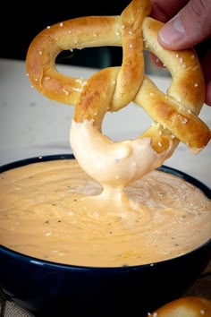 a pretzel being dipped with beer cheese dip