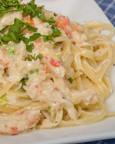 a white plate topped with pasta covered in sauce and garnished with parsley