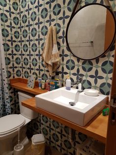 a bathroom with a toilet, sink and mirror in it's corner next to a shower curtain