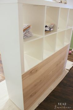 a white book shelf sitting on top of a hard wood floor next to a wall