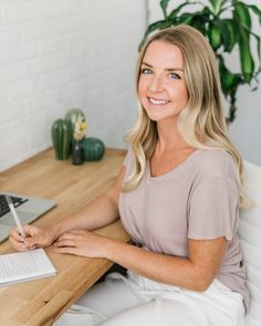 a woman sitting at a desk with a notebook and pen in her hand, smiling