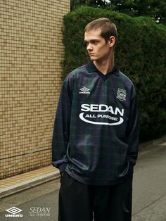 a man standing in front of a building wearing a black and blue shirt with sedan all pro written on it