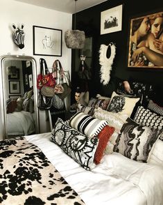 a bed with black and white pillows in a bedroom next to pictures on the wall