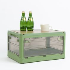 two green beer bottles sitting on top of a mini fridge with the door open to reveal an ice chest