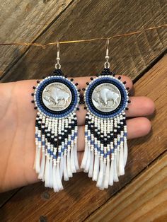 a pair of white and blue beaded earrings sitting on top of a person's hand