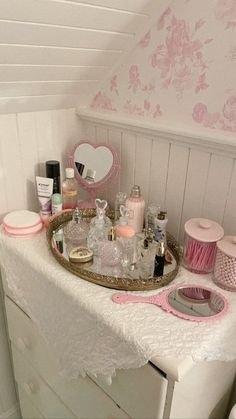 a vanity with pink accessories on it in a white and pink bathroom area next to a mirror