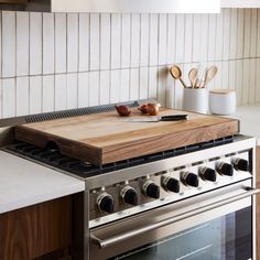 a kitchen with an oven, cutting board and utensils on the counter top