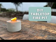 a lit candle sitting on top of a wooden table next to a sign that says diy tabletop fire pit