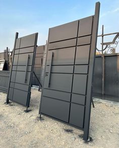 two black gates sitting in the middle of a dirt field next to other metal structures