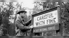 a man standing next to a sign that says careful with fire