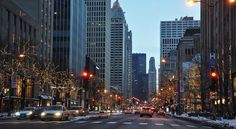 a city street filled with lots of traffic and tall buildings covered in snow at night