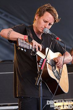 a man playing an acoustic guitar on stage