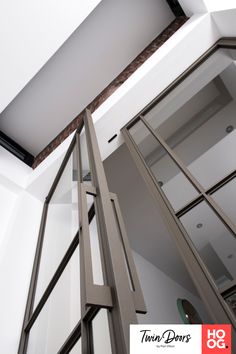 an open glass door in the corner of a room with white walls and ceiling tiles