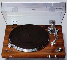 an old record player sitting on top of a wooden table next to a glass case