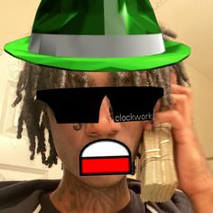 a man with dreadlocks and a green hat on talking on a cell phone