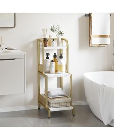 a white bath tub sitting next to a shelf with bottles and soaps on it