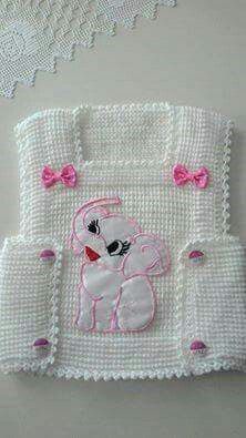 a white crocheted baby blanket with pink bows on the bottom and an embroidered teddy bear in the middle