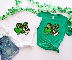 two t - shirts with hearts on them are sitting next to some green streamers