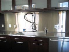 a kitchen with stainless steel counter tops and wooden cabinetry, along with glass doors